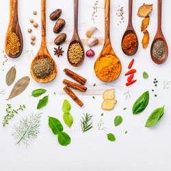 Various herbs and spices in wooden spoons. Flat lay of spices ingredients chilli ,pepper, garlic,dries thyme, cinnamon,star anise, nutmeg,rosemary, sweet basil and kaffir lime on wooden background.