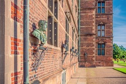 Bronze figures of prominent Danes on a red brick facade of Rosenborg royal Castle in Copenhagen, Denmark