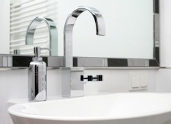Modern chrome tap, faucet, with a soap dispenser besides it