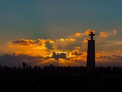 Silhouettes of people and a large cross against the backdrop of a fabulous sunset at the end of Europe, Cabo Da Roca, Portugal
