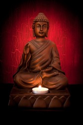 Buddha statue with a candle on a red background