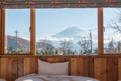 Bed with Fuji mountain view as a background when looking outside the window.