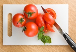 Red tomatoes on hardboard with a knife