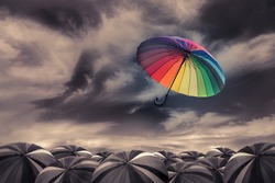 rainbow umbrella fly out the mass of black umbrellas