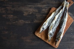 Sun dried fish, salted smelts over wooden background, top view, copy space. Snack  for beer dried smelts.