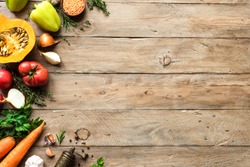 Autumn cooking background with seasonal organic vegetables on wooden table, top view, copy space. Ingredients for autum seasonal soups and dishes.