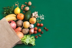 Healthy food background. Healthy vegan vegetarian food in paper bag vegetables and fruits on green, copy space. Shopping food supermarket and clean vegan eating concept.