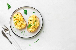 Scrambled Eggs on toasted bread for healthy breakfast or brunch on white background, top view, copy space. 