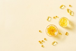 Oil filled capsules (softgel) of food supplements: fish oil, omega 3, omega 6, omega 9, vitamin A, vitamin D3, vitamin E, evening primrose oil, borage oil. Yellow softgels, top view, copy space.
