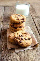 Chocolate chip cookies with milk on paper and rustic wooden table