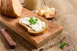 Butter and bread for breakfast, with parsley over rustic wooden background with copy space