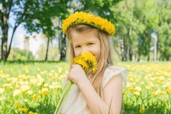 Little girl enjoys the smell of flowers in the meadow