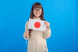 Little girl in glasses with the flag of Japan on a blue background. Education abroad. Learn Japanese.