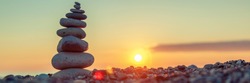 Pyramid of stones on the beach at sunset, beautiful seascape, rest and seaside vacation concept, banner panoramic view