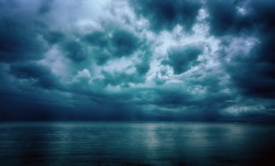 Dramatic stormy dark cloudy sky over sea, natural photo background.