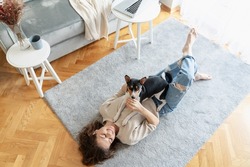 Young happy woman lying on carpet at home with her basenji dog. High quality photo