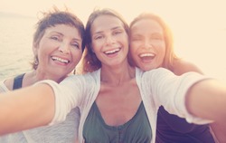 mother and two adult daughters are doing Selfe on the beach