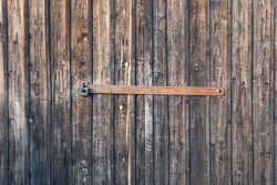 Wooden gate with rusty metal lock and padlock. The texture of the wood is visible on the surface of the boards. Background. Texture.