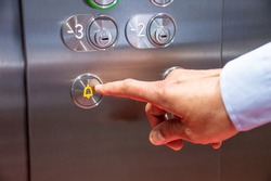 Close-up of hand pressing the alarm button in the elevator