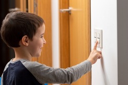 A cropped shot of a little boy switching a light off in his home