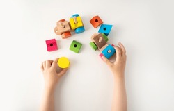 High angle shot of a child hands and wooden toy. The child collects a sorter. Educational logic toys for kids. Children's hands close-up. Montessori Games for Child