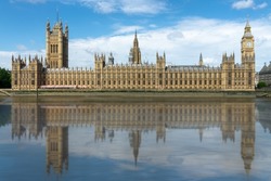 Houses of the UK parliament in Westminster palace, water reflections in the Thames river, London