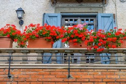 Cute Mediterranean brick balcony window with flowers and a vintage lantern