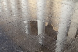 Columns of the building reflected in a puddle