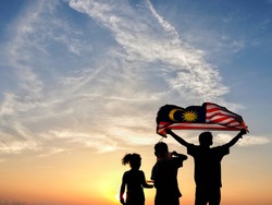 Silhouette of children waving the national flag in conjunction with Malaysia Independence Day. Selective focus. 