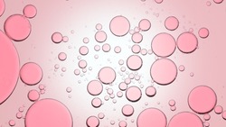 Macro shot of different sized rose oil bubles float in clear liquid against pale pink background | Abstract skin care formulation concept background