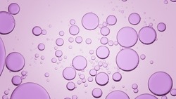 Macro shot of purple different sized transparent oil drops floating in clear liquid on light purple background | Background for skin care product