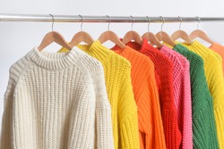 Row of different colorful Knitted, sweaters hang on hangers