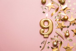 Number 9 gold celebration candle on star and glitter background