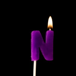 Letter N celebration birthday candle against a black background