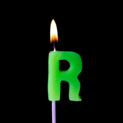 Letter R celebration birthday candle against a black background