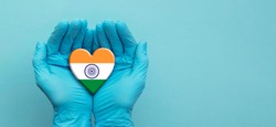 Doctors hands wearing surgical gloves holding India flag heart