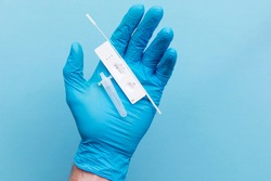 Doctor in blue gloves using a lateral flow covid-19 testing kit