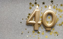 Number 40 gold celebration candle on star and glitter background