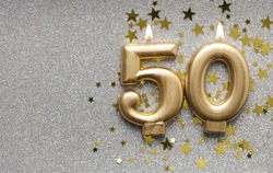 Number 50 gold celebration candle on star and glitter background
