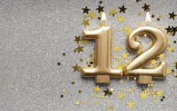 Number 12 gold celebration candle on star and glitter background