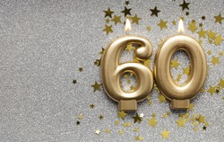 Number 60 gold celebration candle on star and glitter background