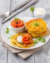 Fried potato pancakes with salmon and sour cream, fritter, roesti, golden crispy crust. Traditional delicious food, breakfast
