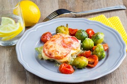 Fish baked with cheese and tomatoes, Brussels sprouts and cherry tomatoes, delicious dish, healthy food