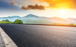 Asphalt road and mountains at beautiful sunset