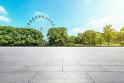Empty square floor and ferris wheel in green city park