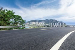 Asphalt road and modern city commercial buildings with skyline by the sea