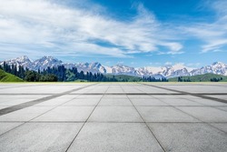 Empty square floor and snow mountain under blue sky. Road and mountain background.