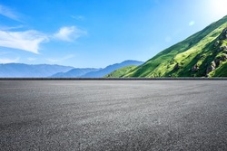 Empty asphalt road and green mountain nature landscape under blue sky. Road and mountains background.