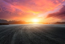 Empty asphalt road and sea with mountain scenery at sunset