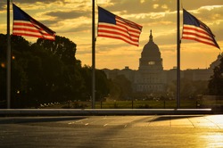 National flags and United States Capitol Building in a dramatic cloudy sunrise - Washington D.C. United States of America